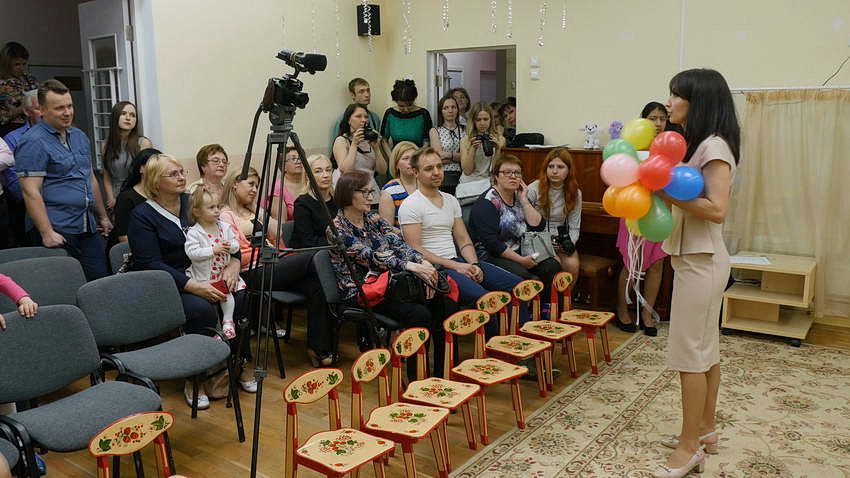 Воспитательница с шарами перед родителями на выпускном